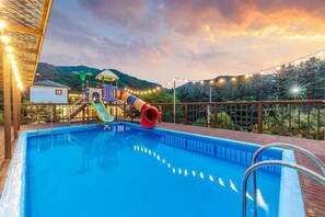 A swimming pool with a slide, a wooden deck, and string lights. - Gapyeong Chaerokji Pension (Gapyeong)