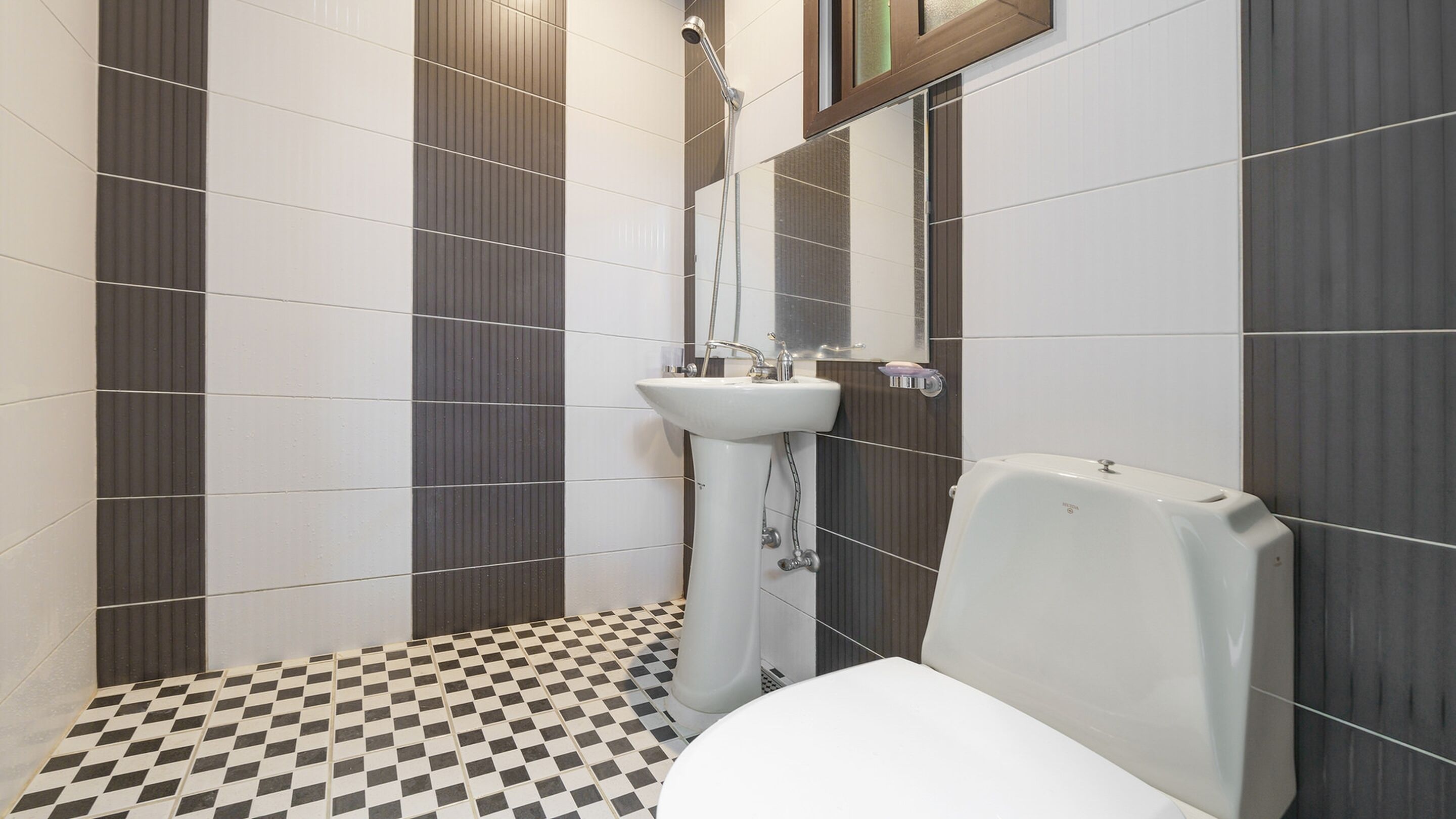 Un baño con piso a cuadros, lavamanos pedestal y un inodoro.