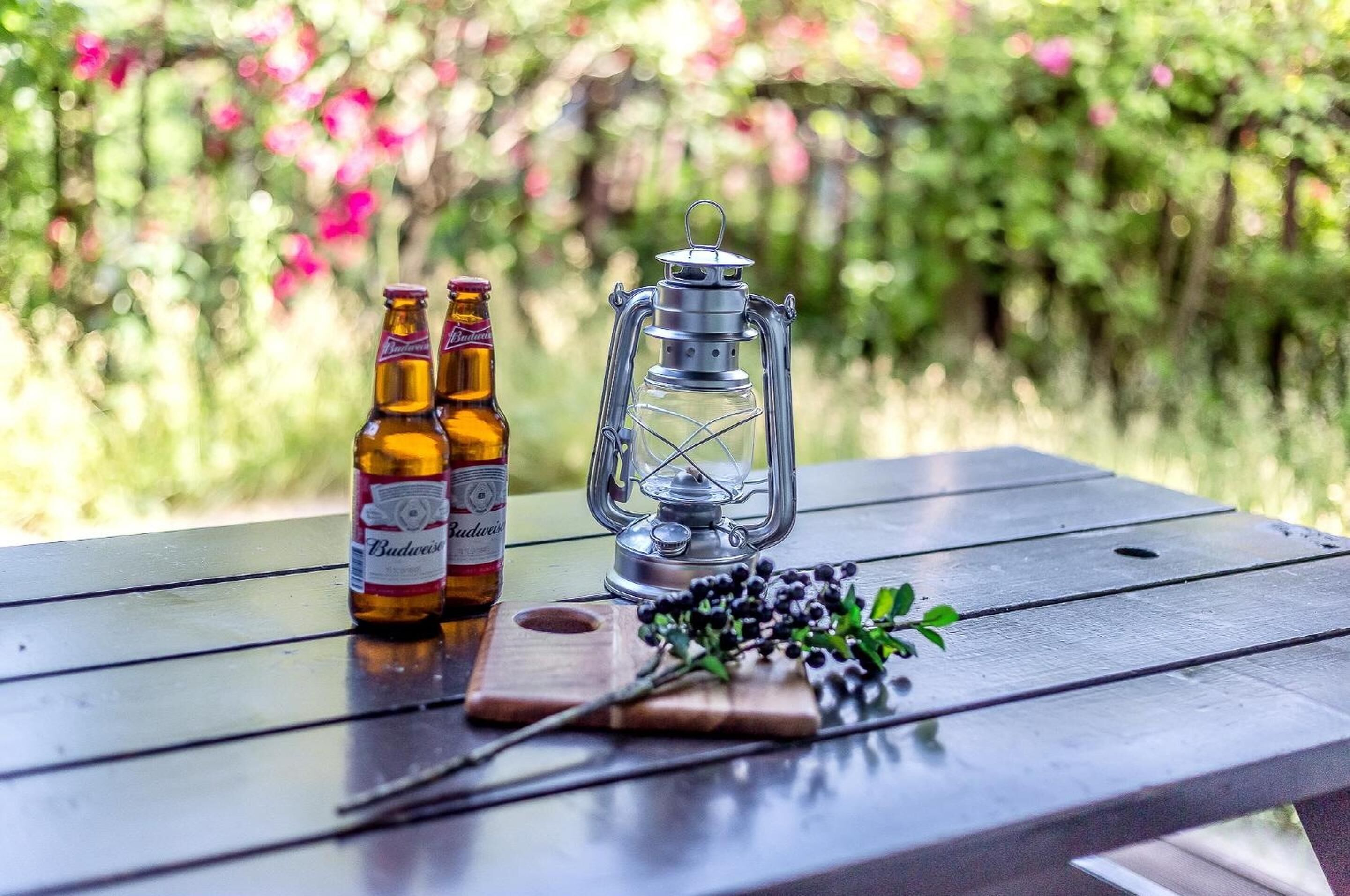 Una mesa de madera con dos botellas de cerveza Budweiser y un farol.