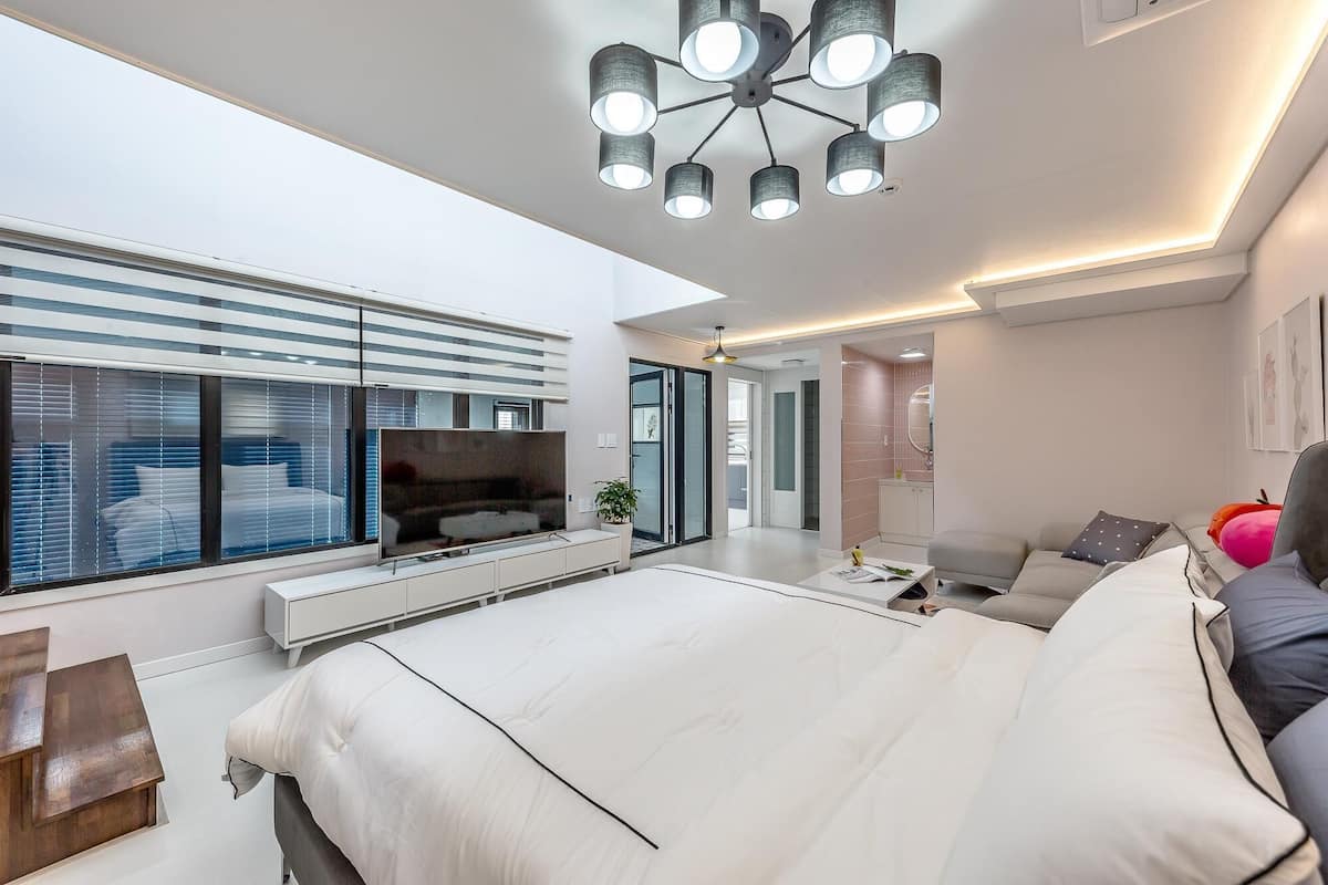 Quarto moderno com cama grande, televisão e luminária no teto.