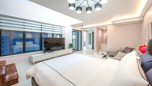 Un dormitorio moderno con una cama grande, televisión y sofá.