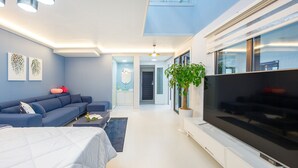 Una sala de estar moderna con un sofá, un televisor de pantalla plana, una mesa de centro y una planta en maceta.