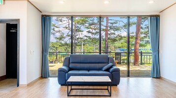A room with a blue sofa, a small table, and a large window with curtains.