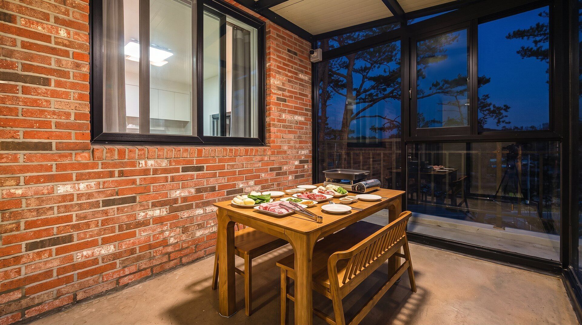 Un coin repas avec un mur en briques, une grande fenêtre et une table mise pour le repas.