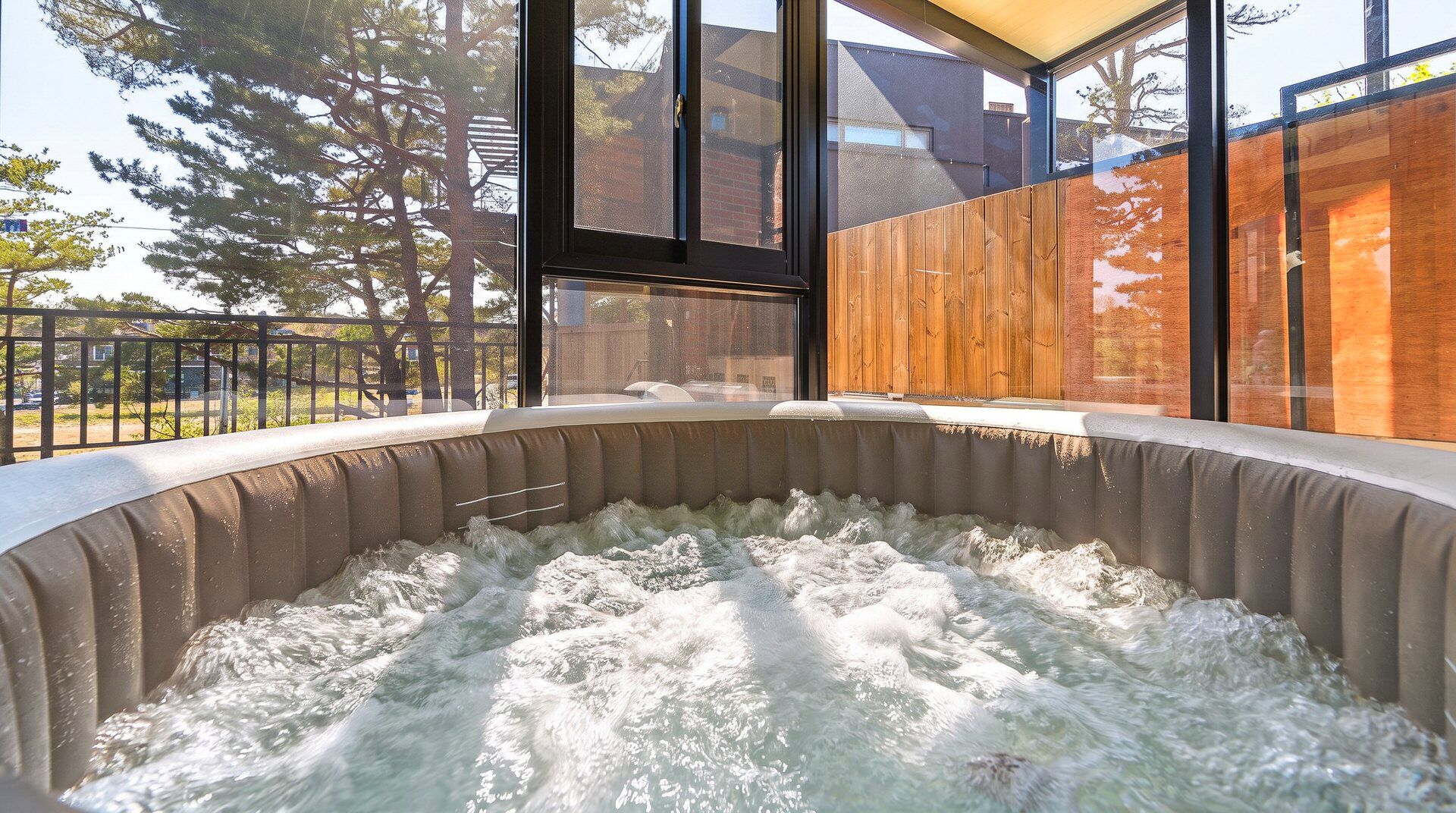 Un bain à remous avec vue sur une terrasse en bois et une structure en verre.