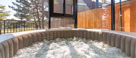 A hot tub with a view of a wooden deck and a glass enclosure.