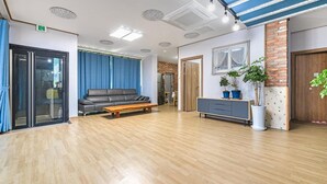 A spacious room with a wooden floor, a grey sofa, a wooden coffee table, a grey cabinet, and a brick accent wall. - Goseong Pinetree Pension (Goseong)