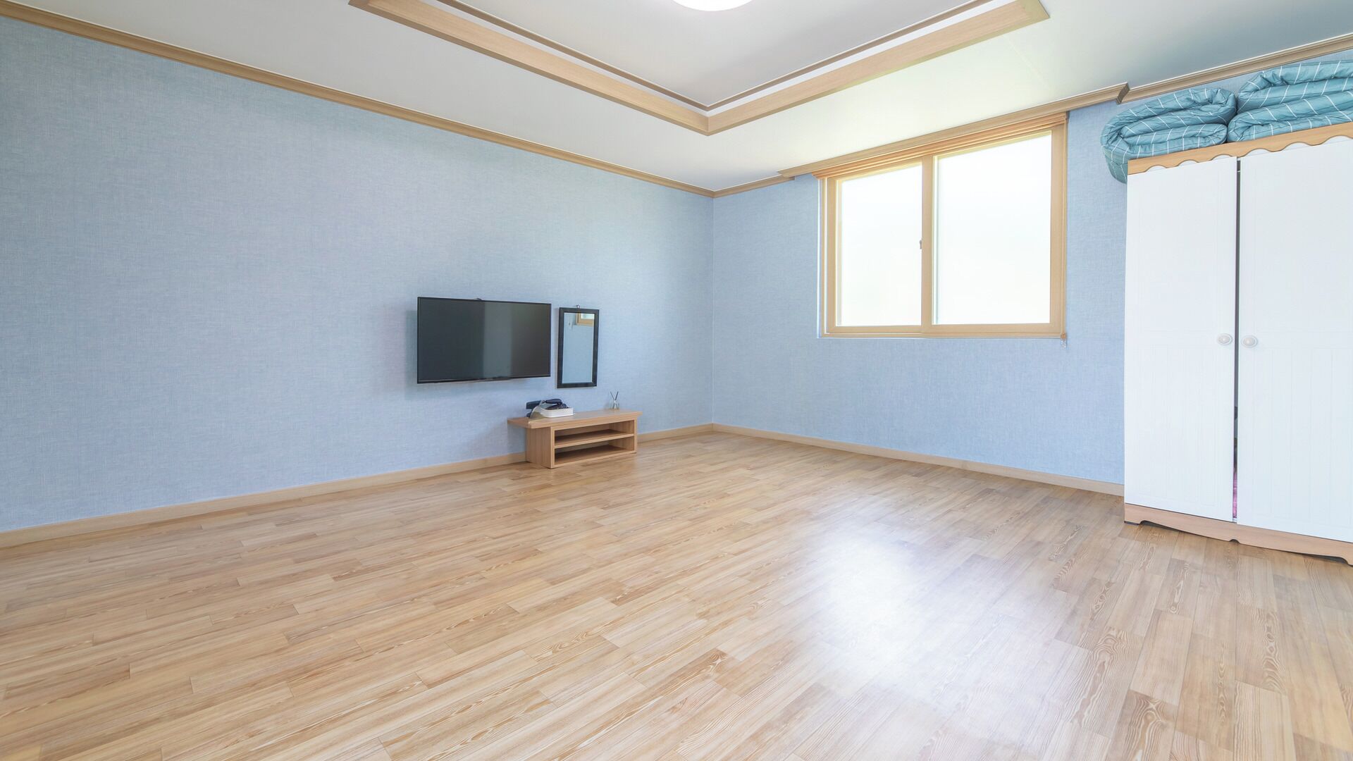 Una habitación con televisión de pantalla plana, un pequeño armario de madera y un guardarropa.