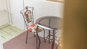 Rincón con una silla y una mesa de metal, suelo de baldosas y pared blanca.