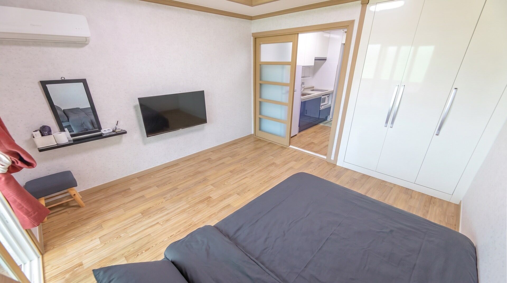 Un dormitorio con cama, televisor, armario y baño visible a través de una puerta.