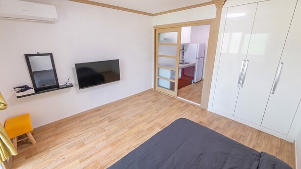 Un dormitorio con cama, televisor, armario y espejo.