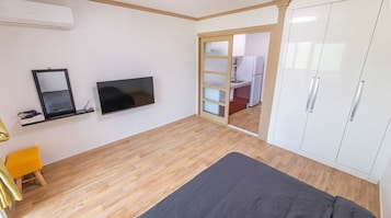 A bedroom with a bed, a TV, a wardrobe, and a mirror.