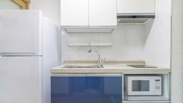 A kitchen with a white refrigerator, a built-in microwave, and a stainless steel sink.