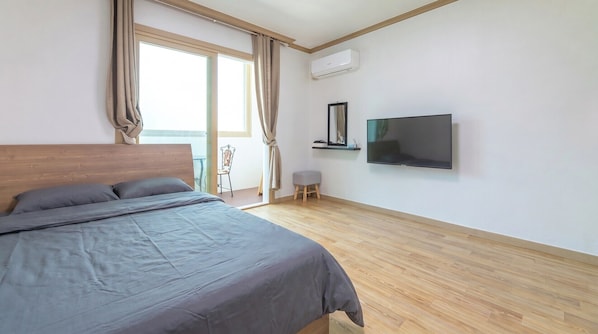 A bedroom with a bed, a television, an air conditioning unit, and a view of the outdoors. - Samcheok Greenhyang Pension (Samcheok)