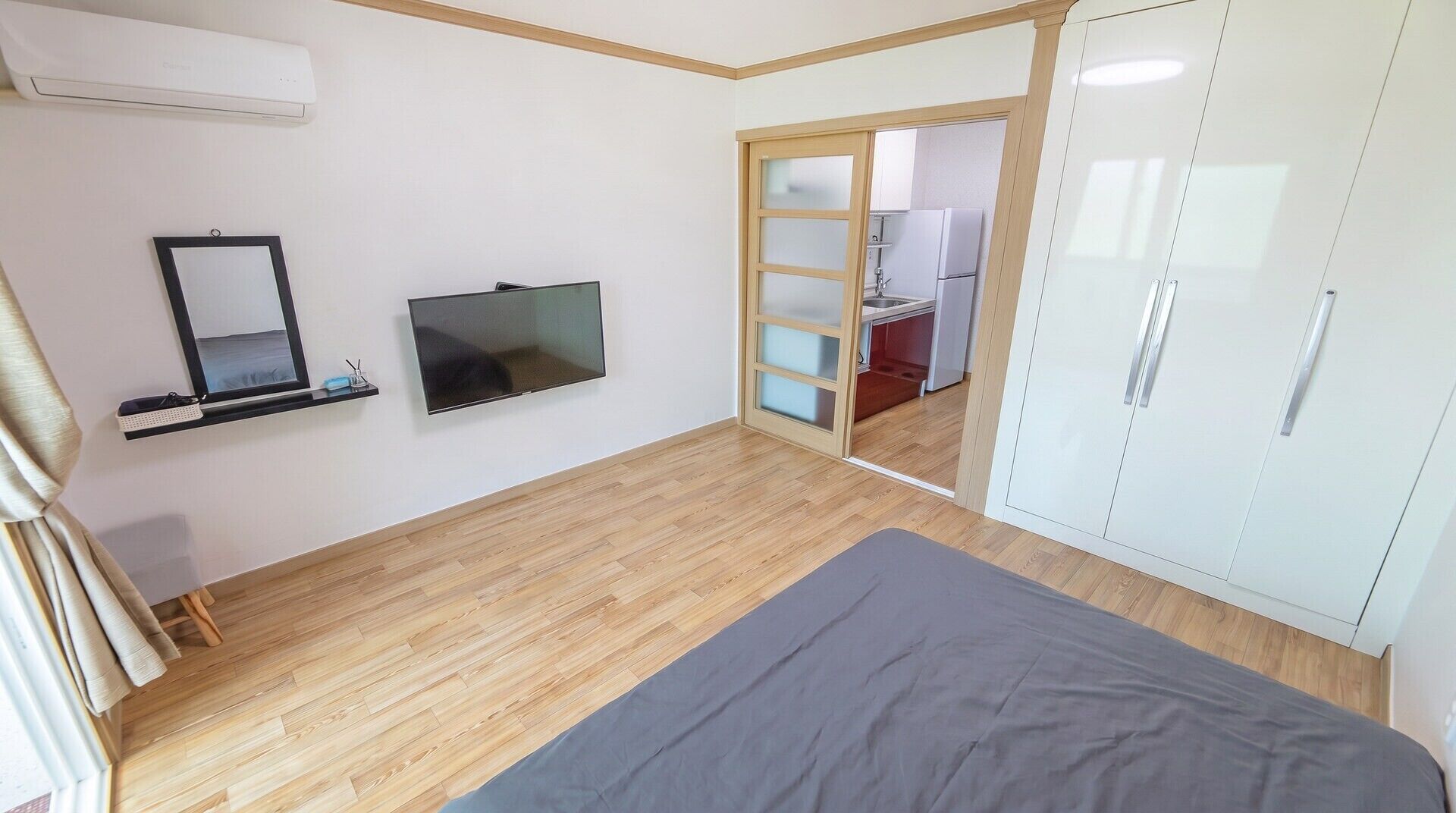 A bedroom with a bed, a TV, a wardrobe, and a mirror.