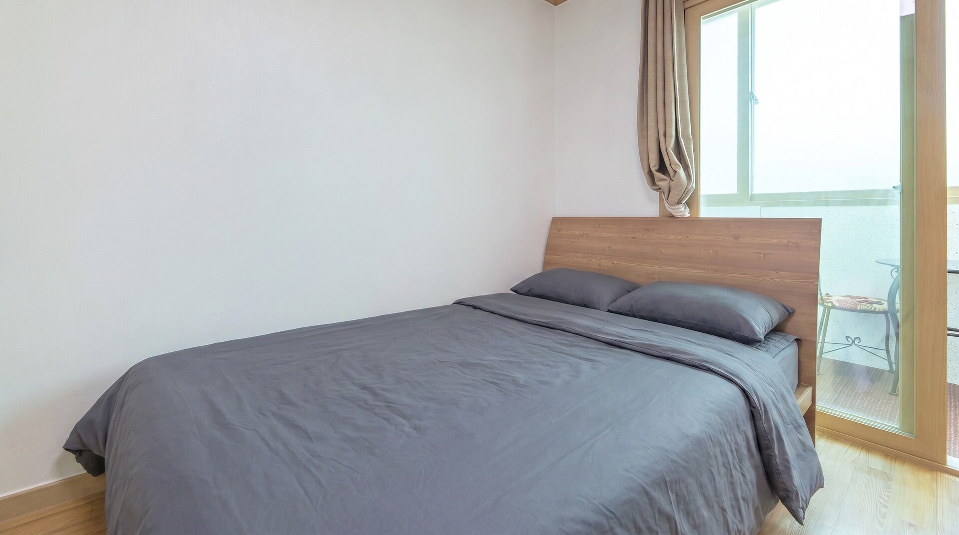 Un dormitorio con cama, cabecera de madera y vista a un balcón.