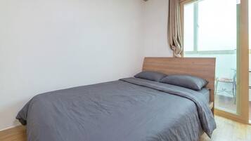 Un dormitorio con cama, cabecera de madera y vista a un balcón.