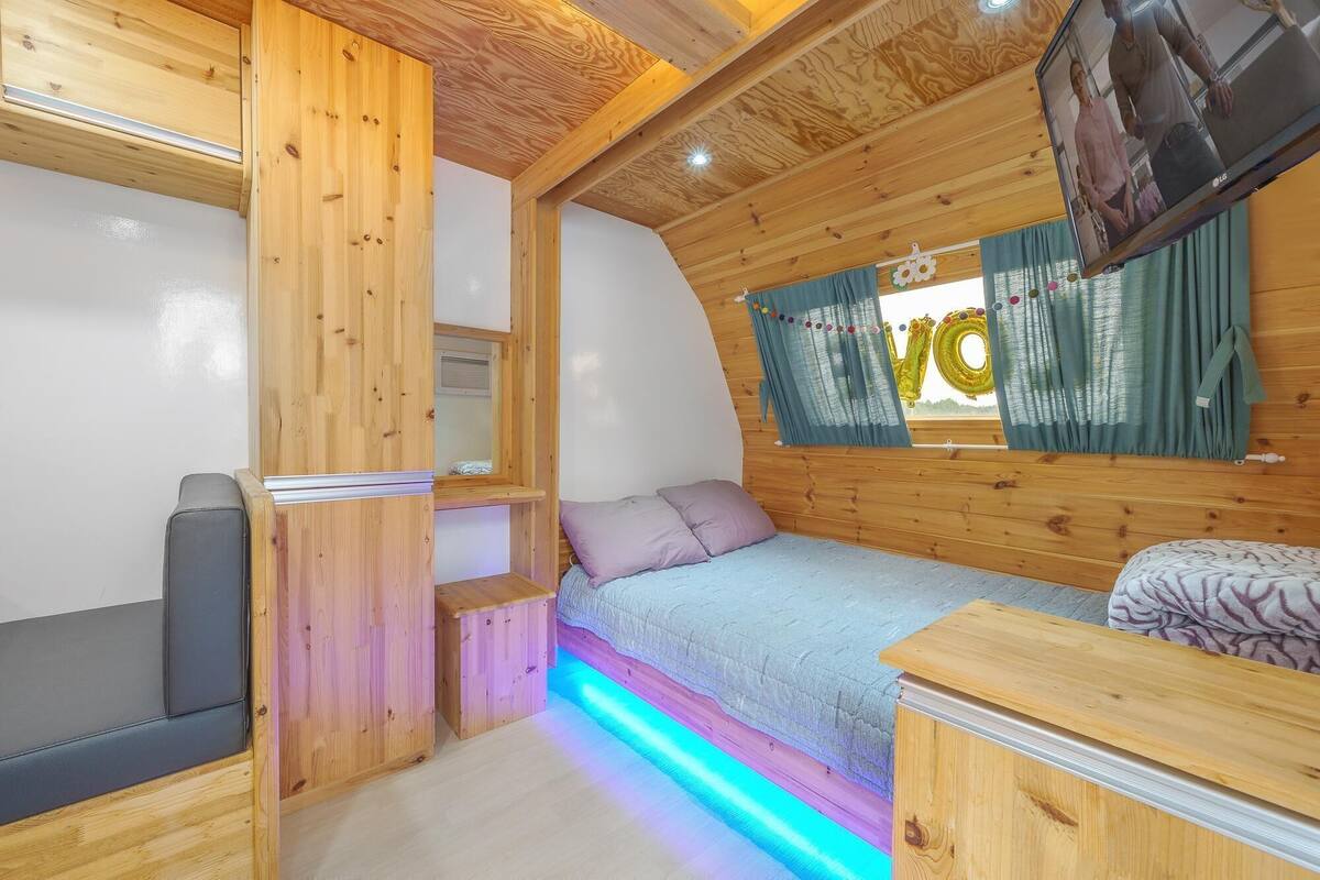 Interior acolhedor de uma cabana, com uma cama, área de estar e televisão.