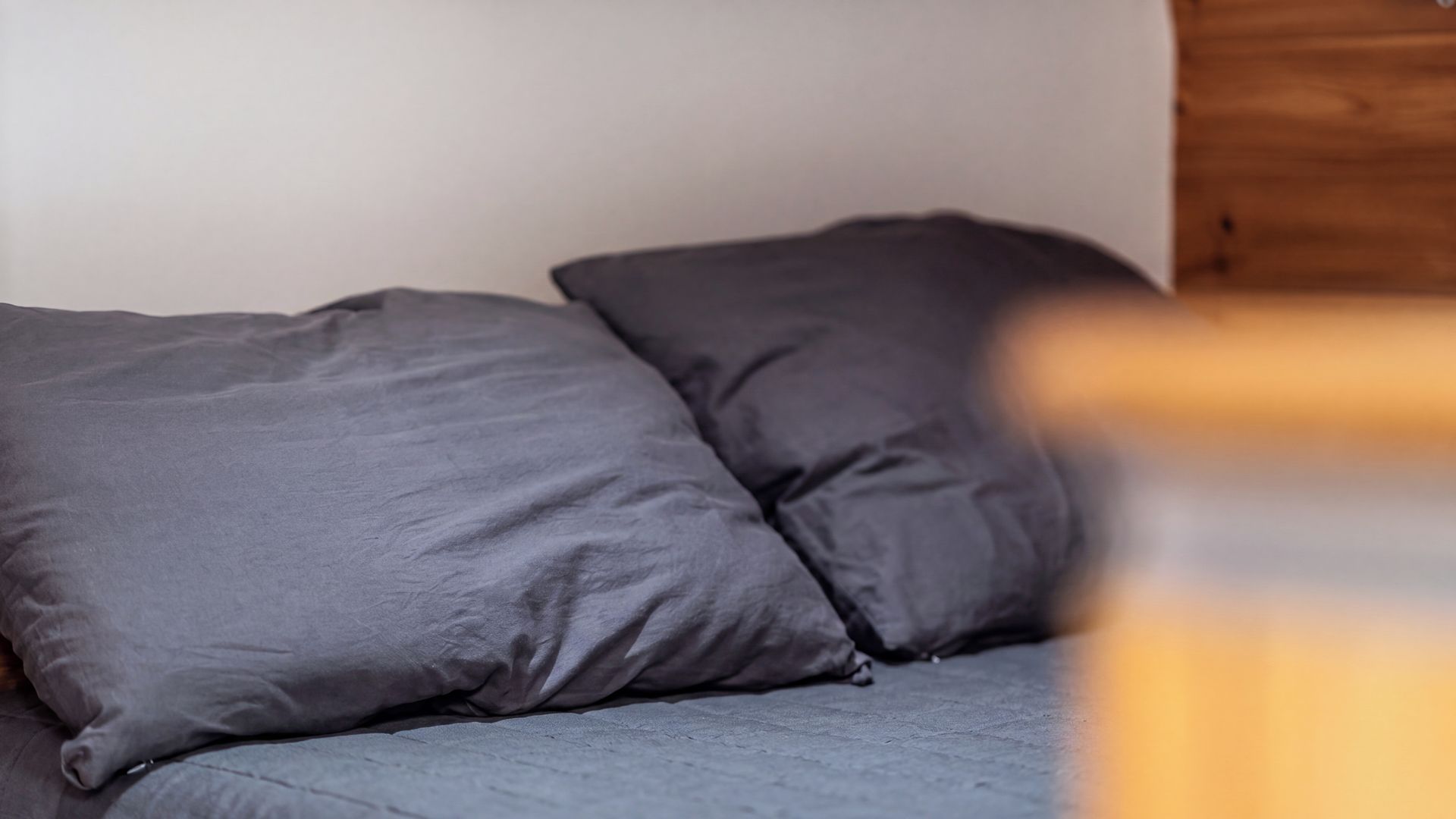 Una cama con dos almohadas y un cabecero de madera.