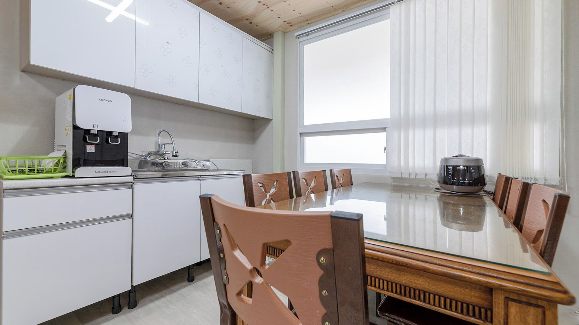 Una cocina moderna con armarios blancos, cafetera y una mesa de comedor con sillas.