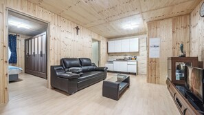 A modern interior with a leather sofa, a glass coffee table, and wooden walls. - Goseong Jjun Camping Pension (Goseong)