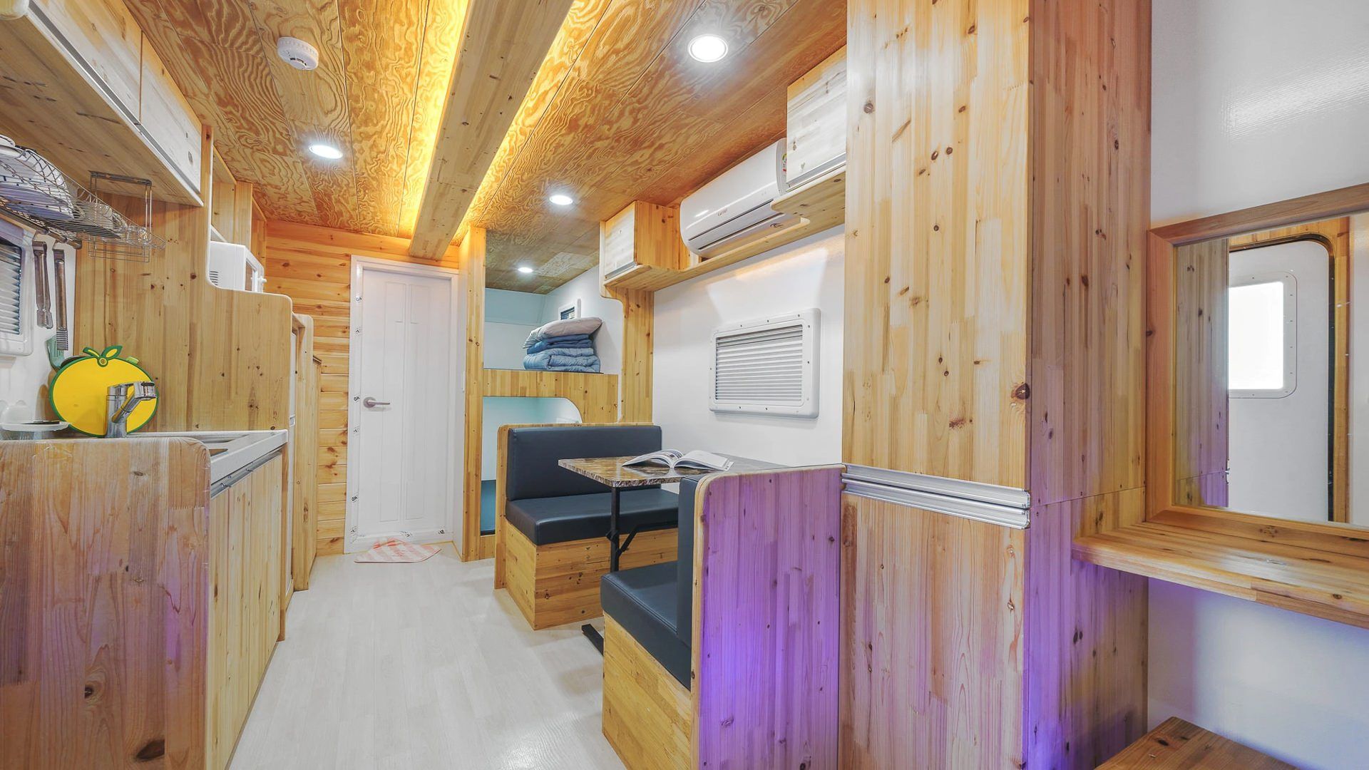 Un pasillo estrecho con paredes de madera, un banco y una mesa con un libro.