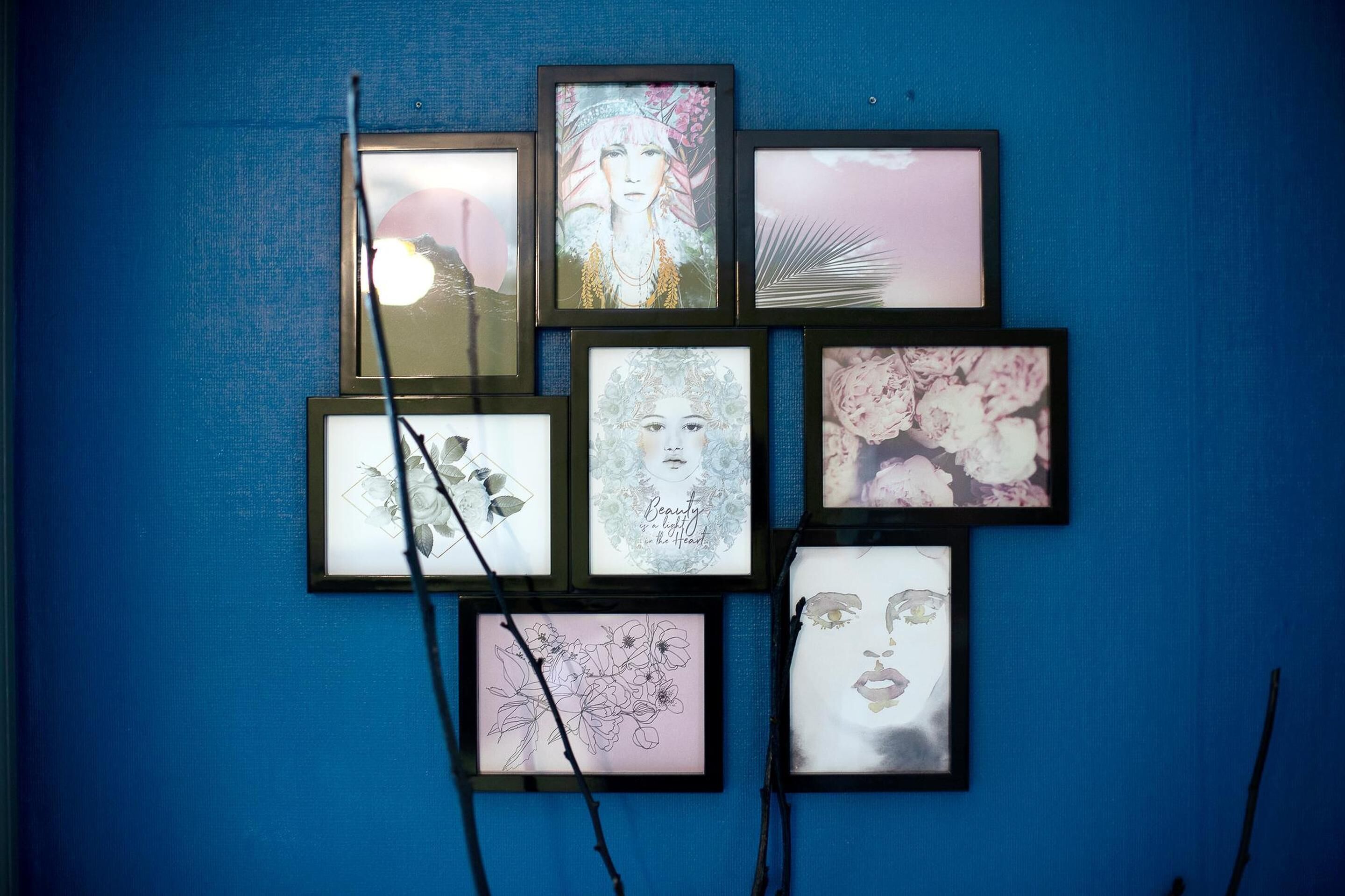 A wall with multiple framed artworks arranged in a grid pattern.
