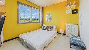 A bedroom with a bed, a window with a view, a bedside table, and a wall with pictures and a dreamcatcher. - Ganghwa Rodemhouse Pension (Incheon)