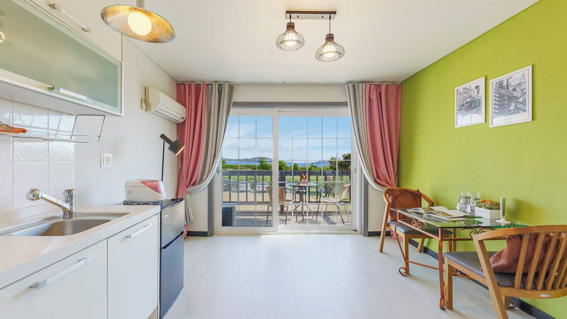 A modern kitchen with a dining area, large windows, and a view of the outdoors.
