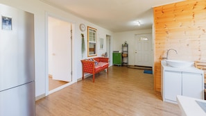 Cuina moderna amb un rentaplat i armaris, un sòl de fusta, i un sofà vermell a la zona de sala d'estar.