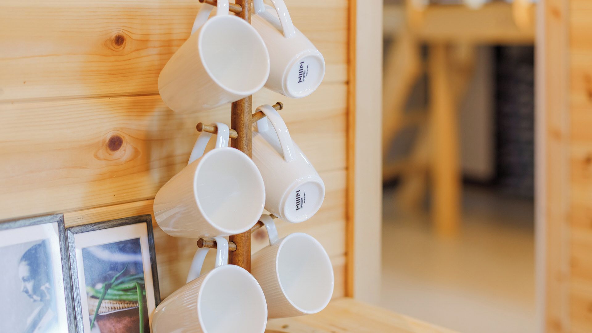 A wooden wall with a rack holding several white mugs.