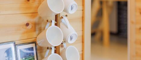 A wooden wall with a rack holding several white mugs.