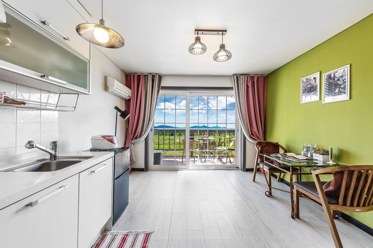 A modern kitchen with a large window, a dining area with a table and chairs, and a view of the outdoors.