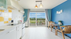 Une cuisine moderne avec un coin repas, une vue sur l’extérieur et un mur d’accent bleu.