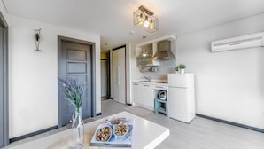 A modern kitchen with white cabinets, a built-in oven, and a hanging light fixture. - Ganghwa Rodemhouse Pension (Incheon)