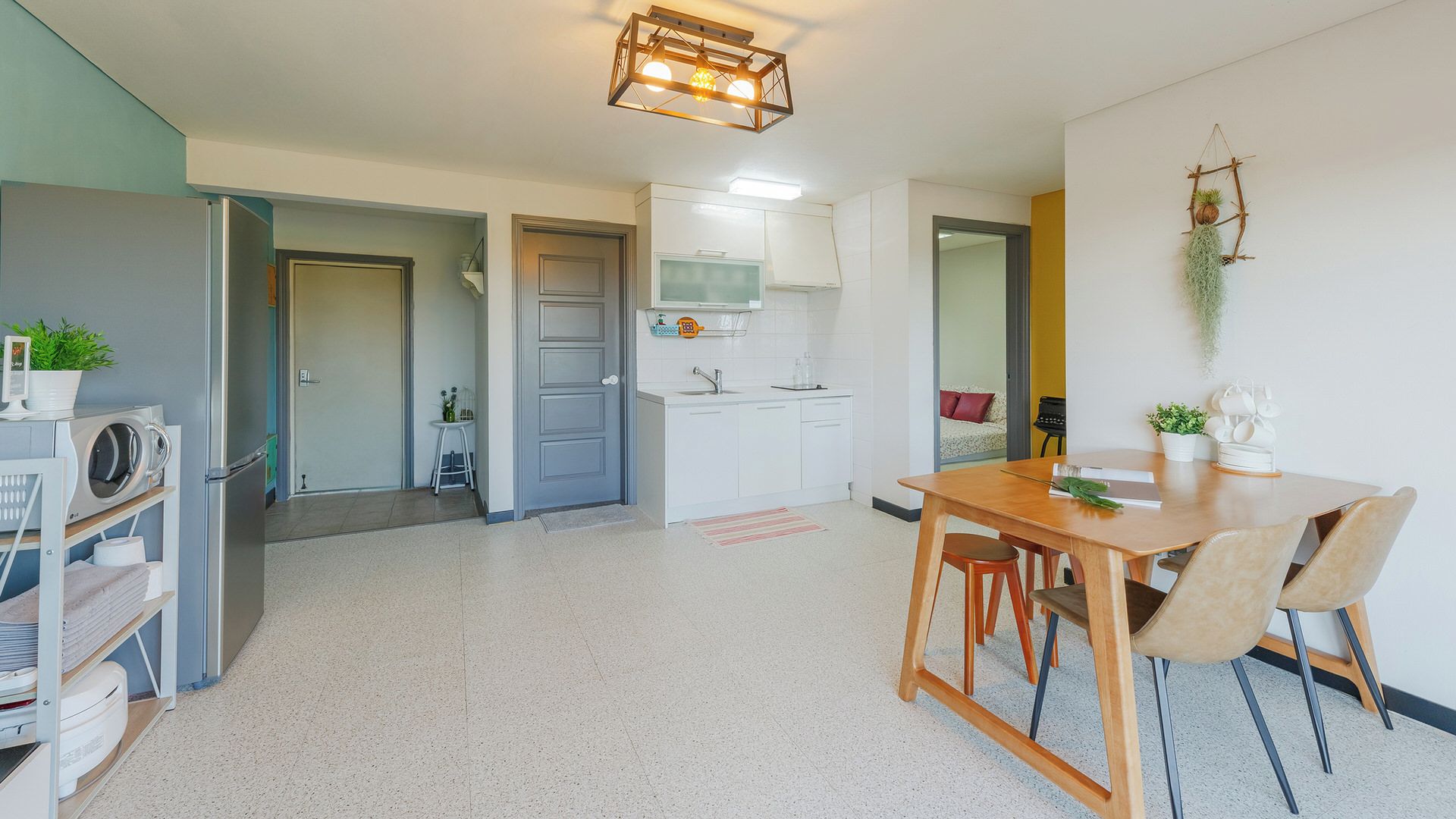 A modern kitchen with white cabinets, a stainless steel refrigerator, and a wooden dining table with chairs.