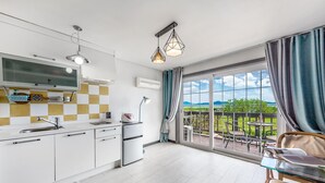 A modern kitchen with a large window, a dining area with a view, and a balcony with outdoor furniture. - Ganghwa Rodemhouse Pension (Incheon)