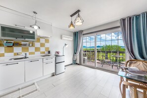 Une cuisine moderne dotée d’une grande fenêtre, d’un coin repas offrant une vue agréable et d’un balcon aménagé avec du mobilier d’extérieur.
