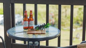Une table en verre avec deux bouteilles de bière Budweiser, une planche à découper en bois et une corbeille de baies.