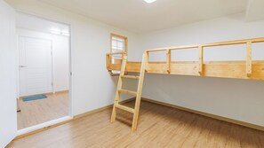 Une pièce avec un lit superposé, une échelle, une porte et une fenêtre.