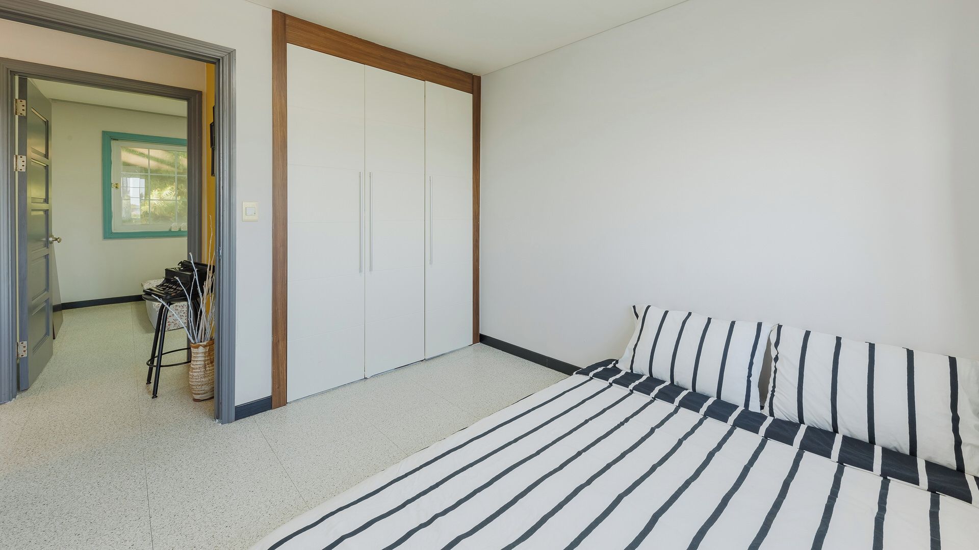 Un dormitorio con una cama, un armario y una puerta que da a otra habitación.