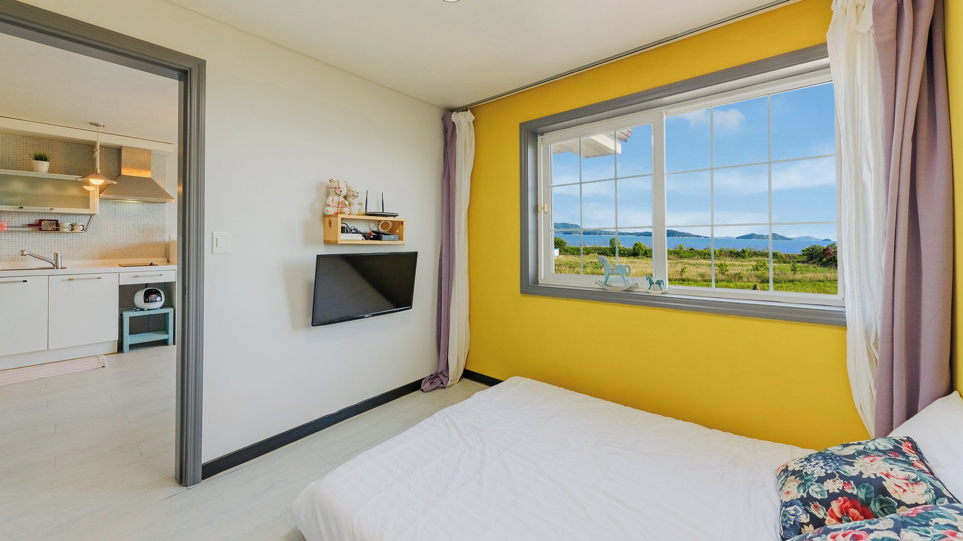 Un dormitorio con cama, televisor montado en la pared y ventana con vista al paisaje.