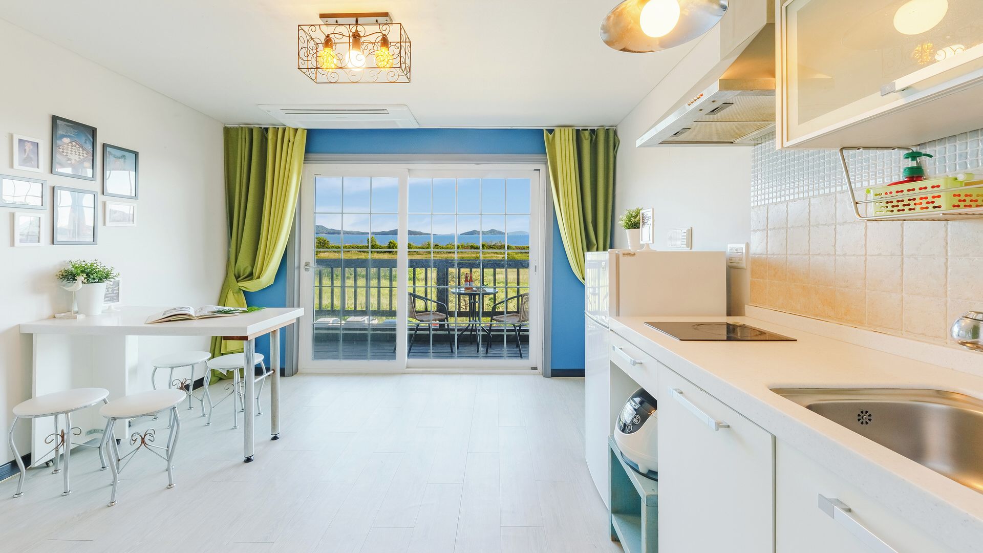 A modern kitchen with a view to the outdoors, a dining area with chairs, and a small table.