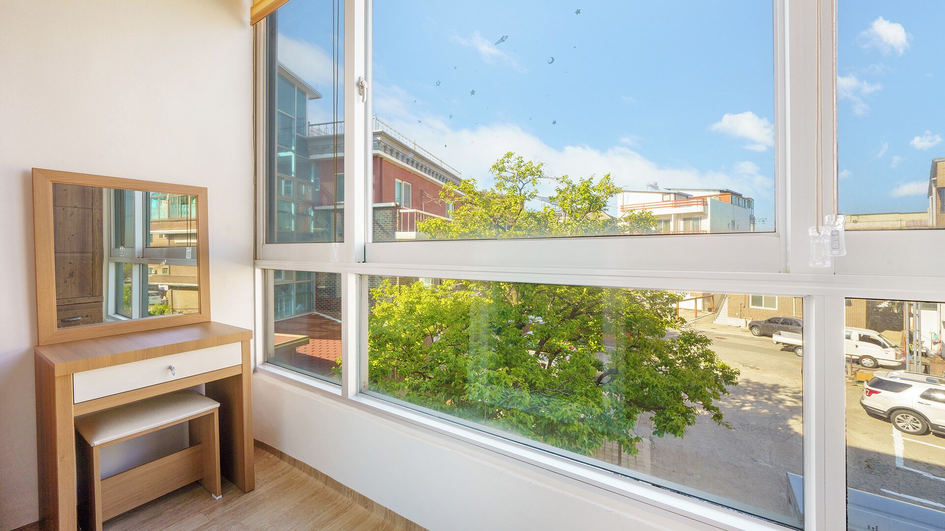 A room with a large window, a wooden desk, and a mirror.