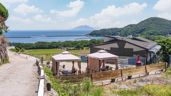 Una propiedad costera con mobiliario exterior, una zona cubierta y vistas al mar y las montañas.