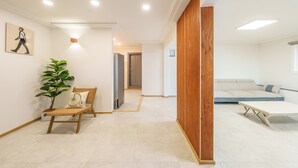 Een modern interieur met een houten scheidingswand, een bank, een stoel en een plant.