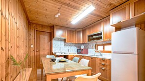 A wooden cabin interior with a dining table, chairs, a kitchen with a refrigerator, microwave, and stove. - Gangnueng Gadunji Pension (Gangneung)