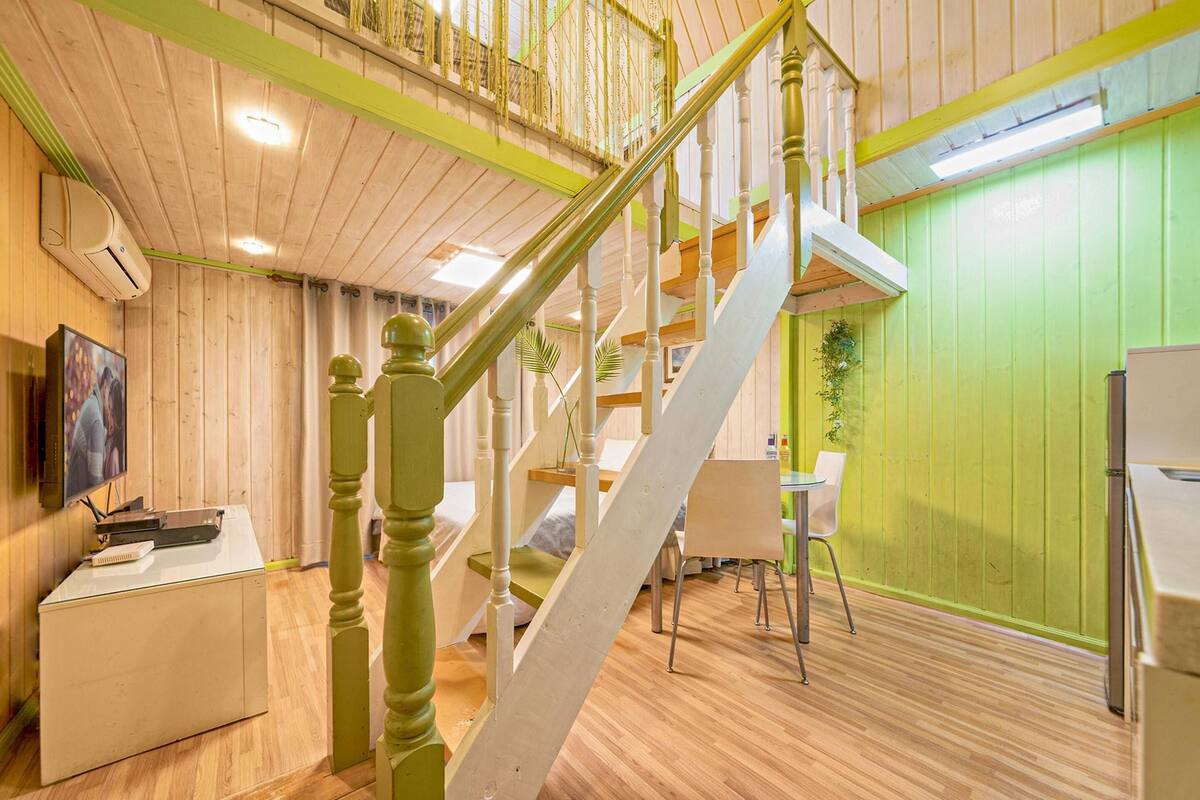A wooden interior with a staircase, a dining area, and a TV on a desk.