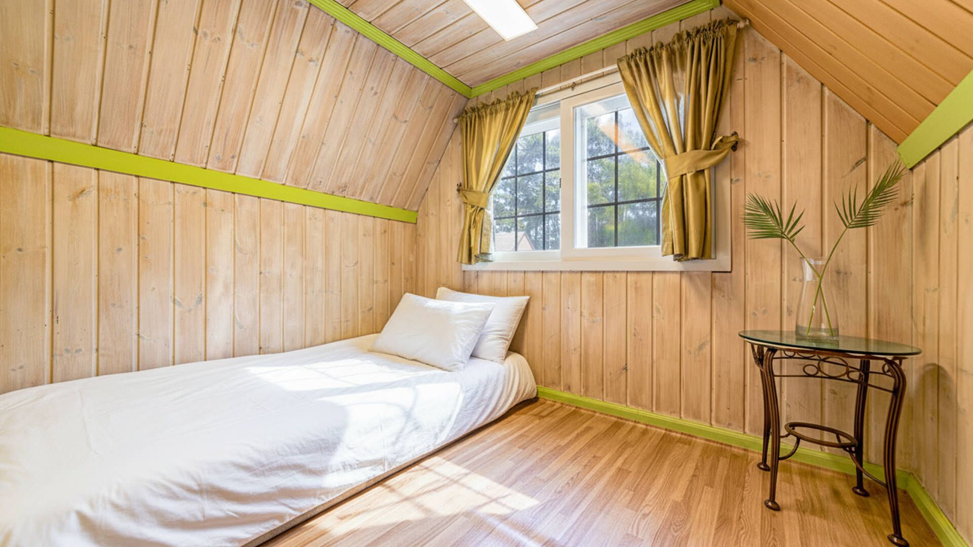 Una cama individual en una habitación con paredes de madera y techo inclinado.