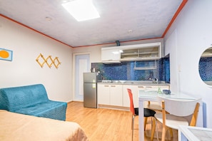 Um espaço compacto com cozinha compacta, área de refeições e sofá.